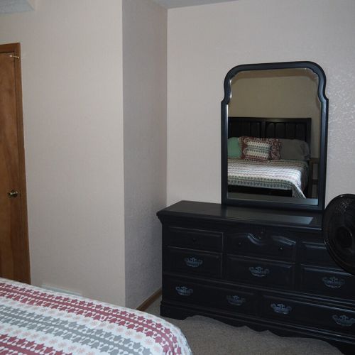 Bedroom #1 (main floor):  features a queen-size bed, nightstands, dresser, mirror, pedestal fan, and closet.