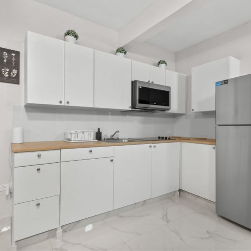 Sleek white cabinets, microwave, and fridge. Ready for snacks.