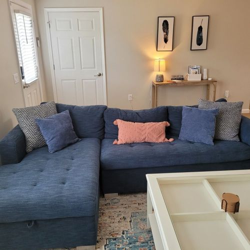 Living room:  the living room features a cozy sectional that unfolds into a double bed. There is also a coffee table, hutch, ceiling fan, a couple portable chairs, a dog bed, and a large smart tv.