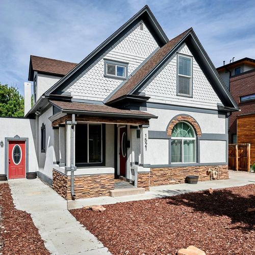 Charming two story home with unique trim, arched window, and a cozy front porch along a landscaped path.