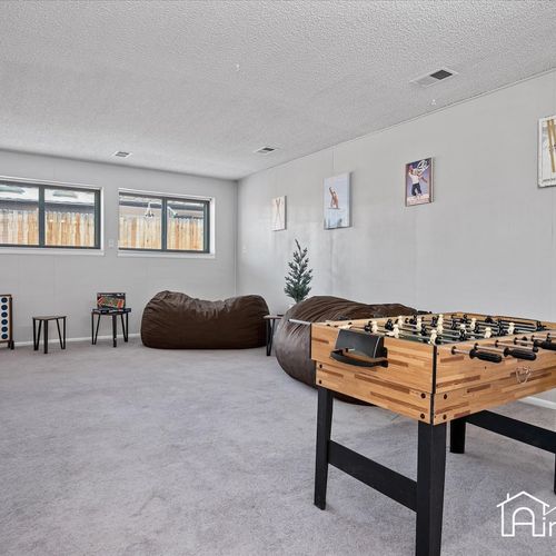 - open concept basement game room with windows, bean bags, foosball, and plenty of space
- family friendly layout ideal for movies, games, or laid back indoor hangouts
- carpeted flooring and neutral walls keep the space light and flexible