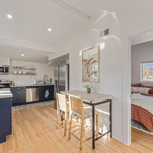 - bright kitchen features open shelving, stainless appliances, and two seater dining nook
- natural wood floors and white walls reflect sunlight beautifully across the space
- thoughtful layout connects to both the bedroom and main living area