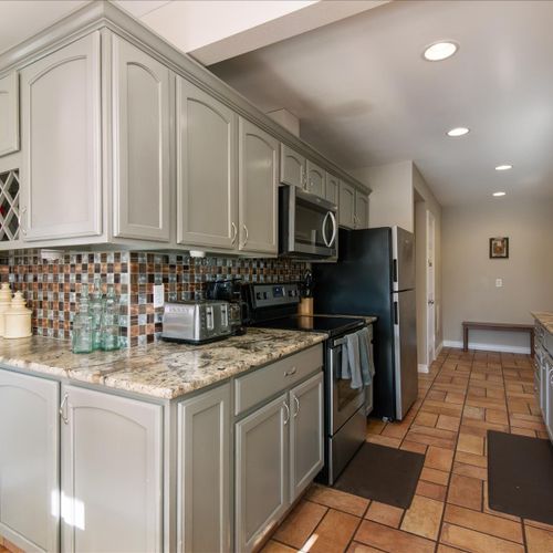 The kitchen includes a stainless steel refrigerator, stove, oven, microwave and coffee maker.