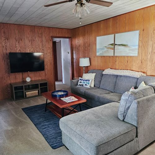 Living room:  very comfy living room with sectional sofa, ceiling fan, coffee table, chair, lamp, fireplace, and streaming television.