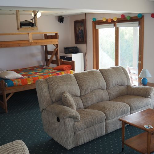 Living room #2 (lower level):  features a sofa and loveseat, bar area, and 3 single beds.