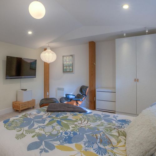 Guest bedroom has a TV and Emmes chair for relaxing.