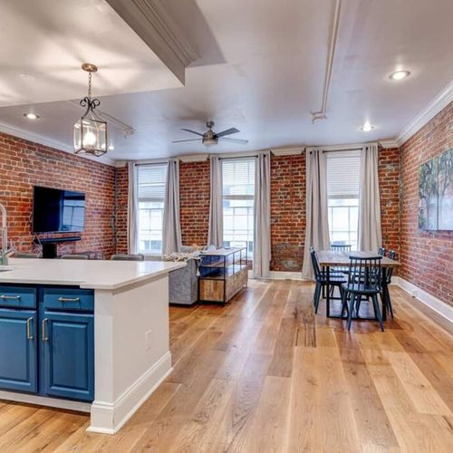 Open living & dining area w/ exposed brick — perfect for gathering w/ family.