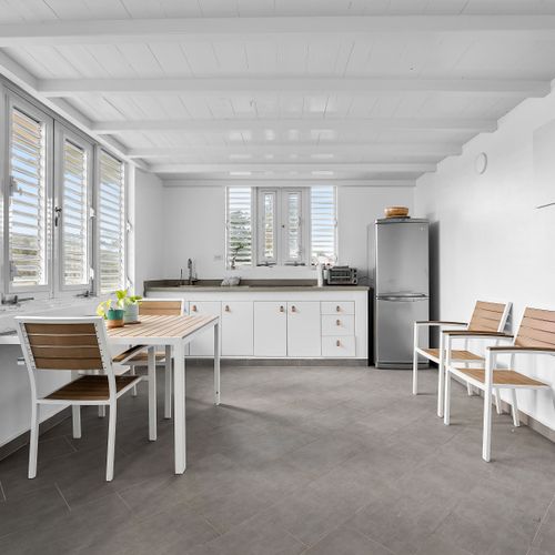 modern kitchen with stainless steel fridge and faucet, dining table and wall art