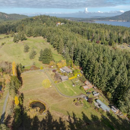 Set on expansive acreage with forest and water views, this secluded retreat offers true privacy, scenic walking paths, and a peaceful island backdrop.