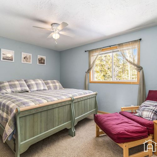 The main bedroom boasts a cozy king bed with cottage linens, built-in closet space, and a chair that converts into a twin-sized bed.