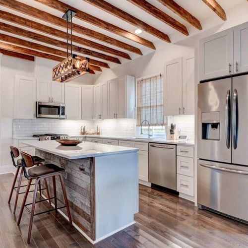 Sleek white kitchen w/ stainless appliances & island seating for casual mornings.
