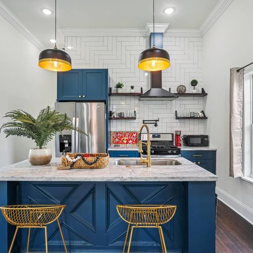 Newly renovated kitchen w/ bold blue cabinets, open shelving & pendant lights.