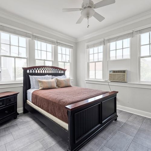 Wake up to sunshine in this bright and airy bedroom, featuring large windows, a cozy bed, and chic decor for a peaceful retreat.