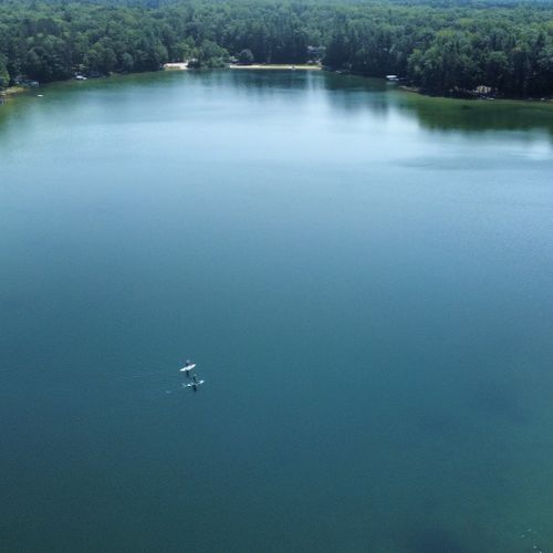 Exterior:  a high-level view of cub lake, with some people paddleboarding across the lake.