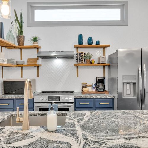 Stylish kitchen w/ open shelving, bold tile backsplash, & stainless appliances ready to use.