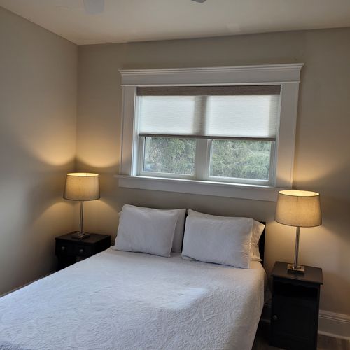 Bedroom #1 (main floor):  features a queen-size bed, ceiling fan, window a/c unit, nightstands, lamps, chair, dresser, mirror, and a closet.