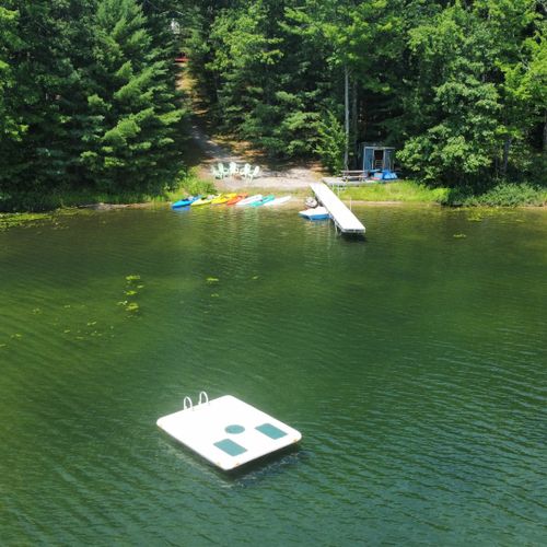 Exterior:  an aerial view of the private lakefront with the private swim raft in the forefront.