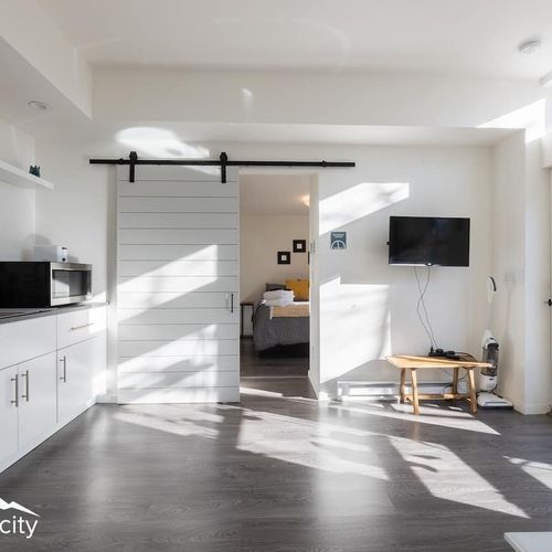 - open plan space with smart tv, dining area, and kitchenette seamlessly connected
- sliding barn door leads to a comfy private bedroom for restful nights
- bright natural light fills the room, making it feel cheerful and welcoming