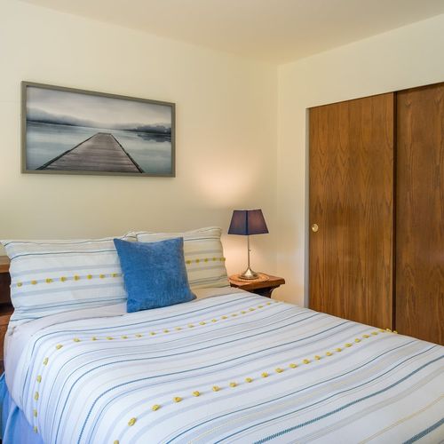 Guest bedroom with a large closet, luggage racks, and full bathroom in the hallway.
