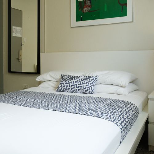 Luxury and comfort combined. This spacious bedroom features an opulent queen bed with extra pillows, inviting you to sink in and enjoy a truly relaxing experience.
