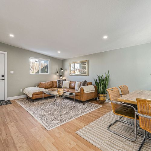 - large leather sectional and four seat dining table share this elegant open plan living area
- matching rugs and soft neutral tones tie the two zones together seamlessly
- modern, welcoming space great for meals, games, or movie nights with friends