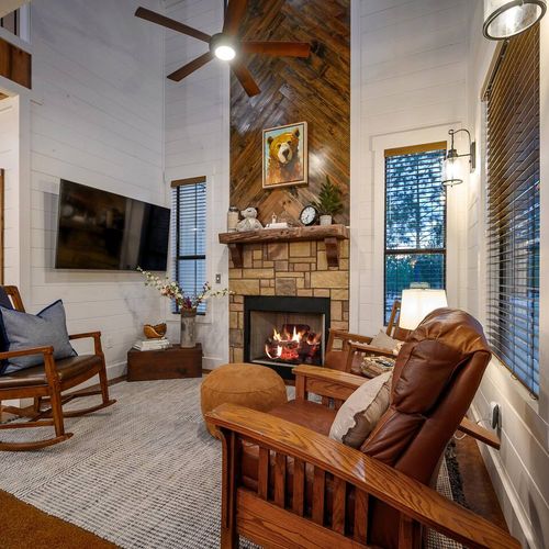 The living room has a stone fireplace at the heart of it.
