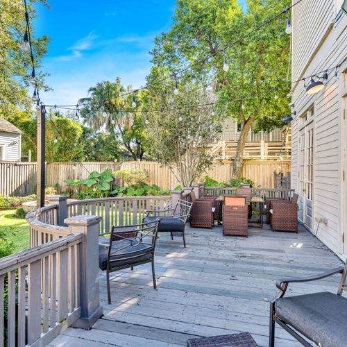 Spacious backyard deck with comfortable seating, string lights, and lush greenery—perfect for outdoor relaxation or entertaining.