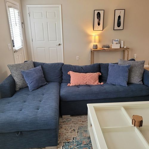 Living room:  the living room features a cozy sectional that unfolds into a double bed. There is also a coffee table, hutch, ceiling fan, a couple portable chairs, a dog bed, and a large smart tv.