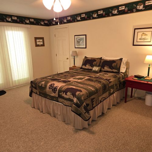 Bedroom #1:  the cabin has a large primary bedroom with a queen-size bed, desk, comfy chair, ceiling fan, dresser, and closet.