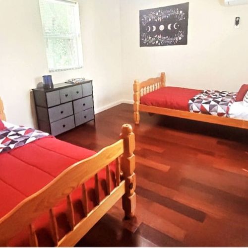 Bright bedroom with two cozy twin beds and warm wood flooring.