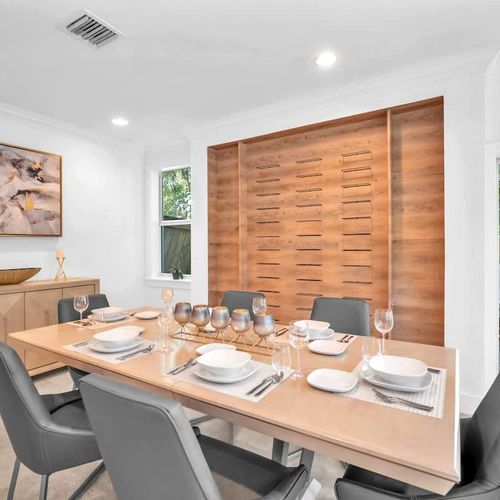 Dine in style in this elegant space, featuring a chic wood-accent wall, modern seating, and a beautifully set table. Perfect for shared meals and great conversation, this cozy setting blends warmth and sophistication with a lovely view.