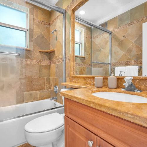 Elegant bathroom with warm-toned tile, a spacious vanity, and a glass-enclosed shower for a relaxing stay.