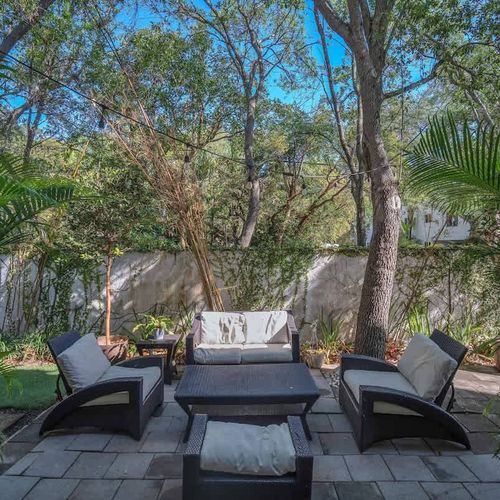 Unwind in this serene backyard oasis! Cozy seating, lush greenery, and string lights create the perfect setting for morning coffee or evening conversations under the trees