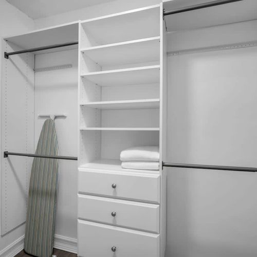 Stay organized with this spacious walk-in closet—plenty of shelving, hanging space, and even an ironing board to keep you looking sharp.