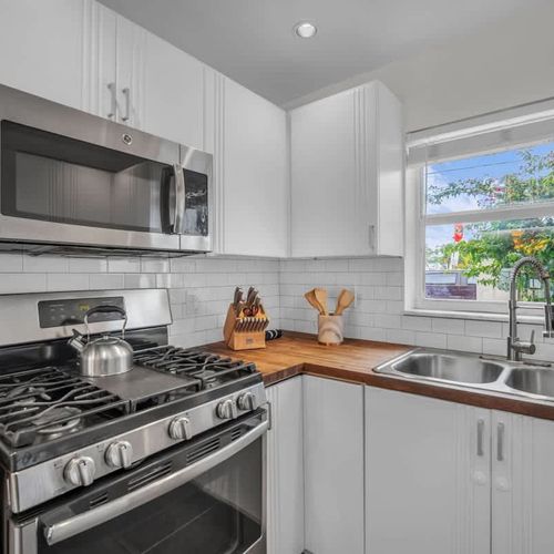 Whip up meals in this bright, modern kitchen—complete with stainless steel appliances, butcher block countertops, and a sunny window view. A cozy, homey space that makes dining in a delight!