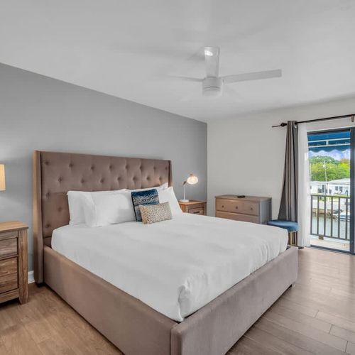 Unwind in this serene primary suite featuring a plush king bed, warm lighting, and direct access to a private balcony. Perfect for peaceful mornings and cozy nights in your home away from home.