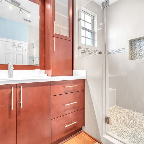 Enjoy the comfort of a private, fully attached bathroom in Bedroom 1, complete with a large vanity mirror cabinet, a bright, clean atmosphere, and a roomy walk-in shower.
