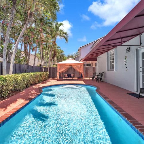 Enjoy sunny days by the private pool, surrounded by lush greenery, cozy umbrellas, and a charming patio.