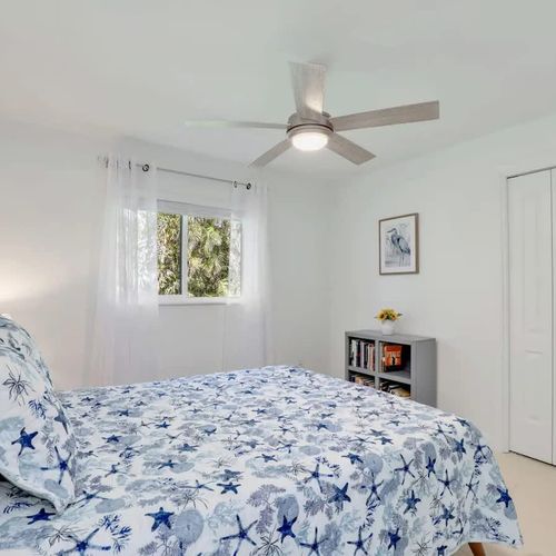 Bedroom 1 features a spacious queen bed with plush pillows, crisp linens, a private TV, and tranquil lake views right outside the window.