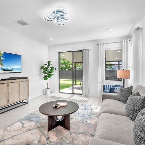 Relax in the bright and airy living room featuring a plush, inviting couch, tasteful décor, and a big screen for your favorite films and series.