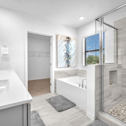 Bathroom 1 features a generous bathtub, a separate walk-in shower, and a spacious vanity for added convenience.
