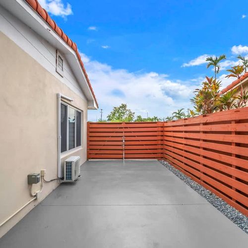 This serene outdoor space offers mature trees, a grassy yard, a cozy swing seat, and a patio area perfect for enjoying the fresh air.