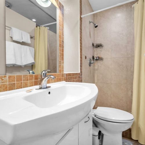 Full bathroom featuring a shower, vanity, and standard amenities.