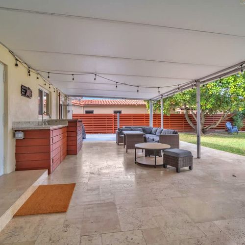 Relax in a spacious, fully fenced backyard with lush green space, shady trees, a charming swing set, and a patio perfect for outdoor lounging.