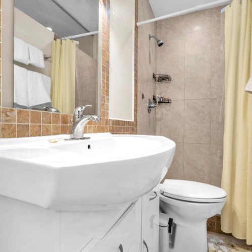 Full bathroom featuring a shower, vanity, and standard amenities.