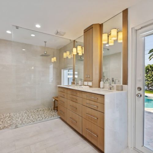 Elegant ensuite bathroom featuring modern design, clean lines, and natural light with views of the outdoor pool.