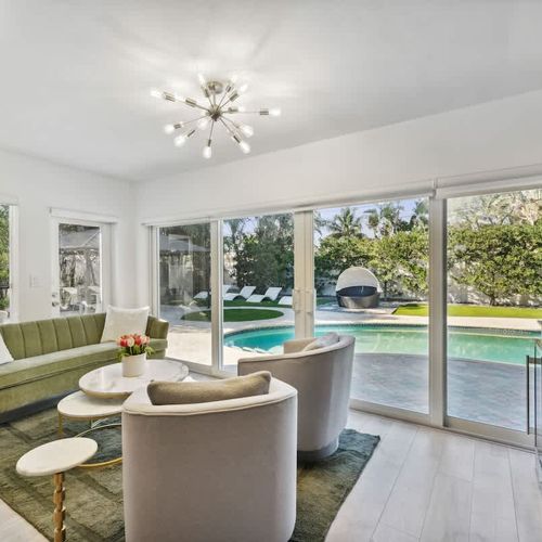 Stylish secondary living area featuring comfortable seating and large glass doors that open to relaxing pool and backyard views.