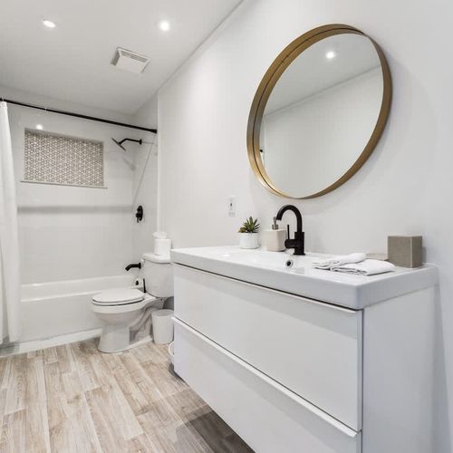 Minimalist bathroom with a modern sink vanity and a bathtub with shower enclosure.
