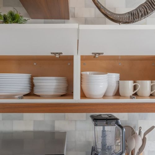 Drawers and cupboards are neatly organized and supplied with essential cookware, dishware, and dining items.