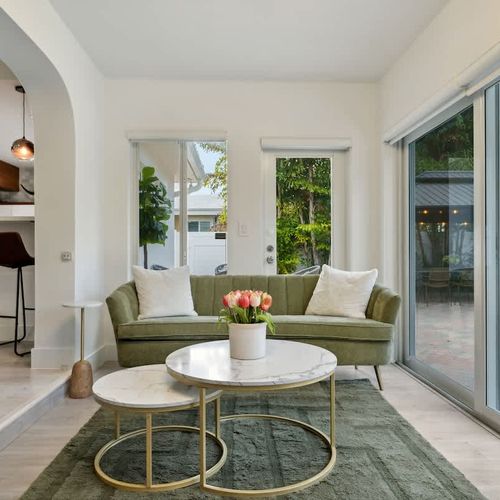Stylish secondary living area featuring comfortable seating and large glass doors that open to relaxing pool and backyard views.